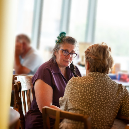 Vie and a client sat in a café, engaged in conversation, with a relaxed atmosphere.