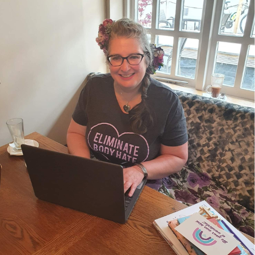 Vie sits at a table, working on a laptop in a cozy café setting.